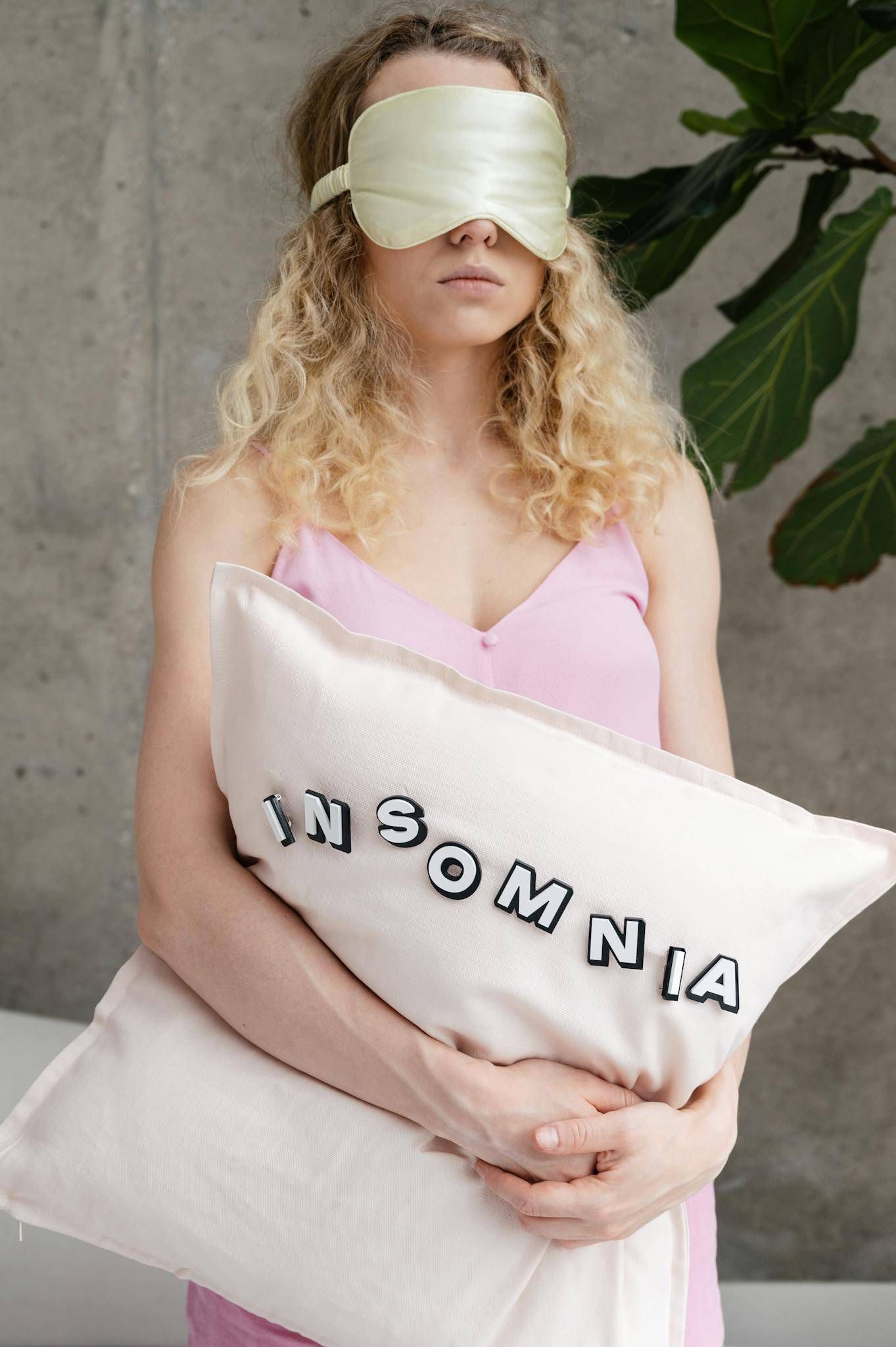 Woman with sleep mask and insomnia pillow symbolizing sleep issues.