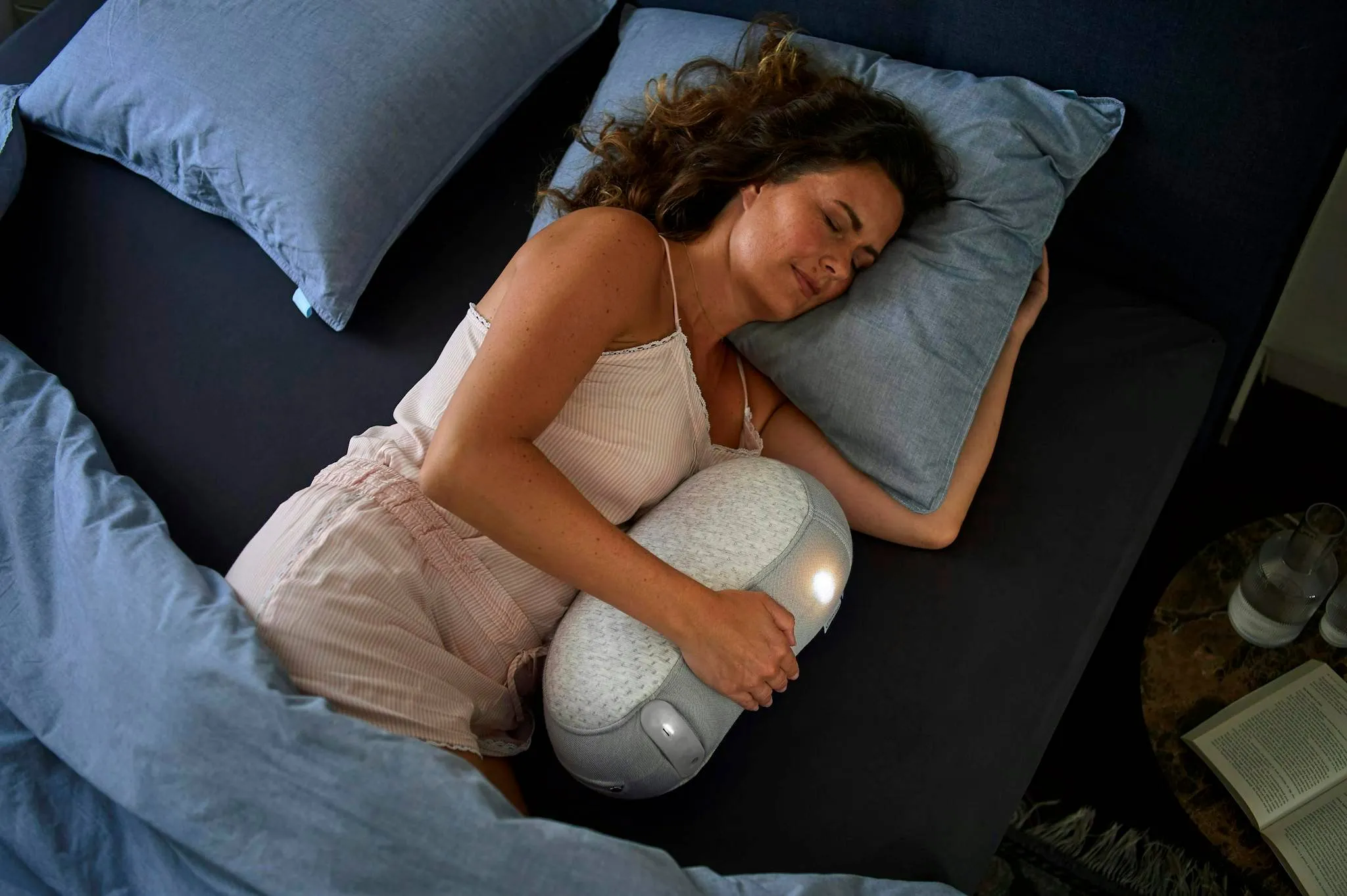 Relaxed woman lying in bed hugging a sleep robot for restful slumber.